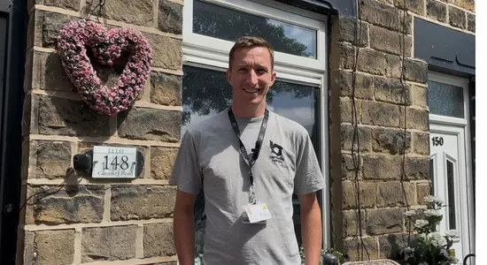 A Plumber From Berneslai Homes Standing In Front Of A Home