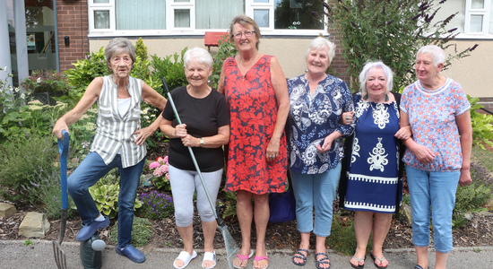 A group of tenants standing outside in front of the gardens at Pendon House.png